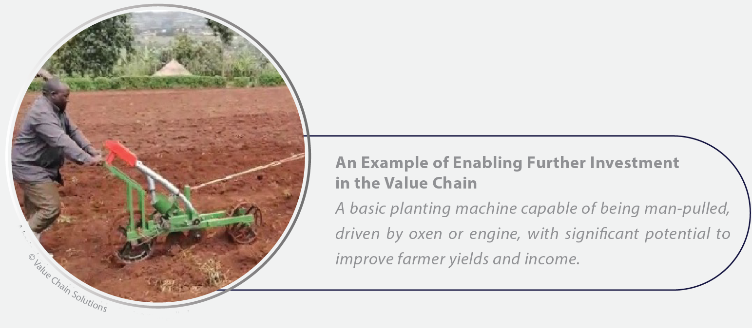 A man pushing a basic planting machine in a field.